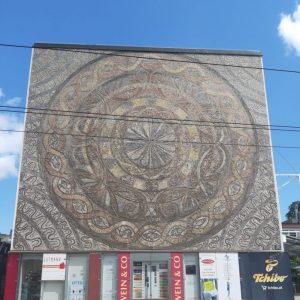 Großes Mosaik an einer Hauswand: Konzentrische Kreise in Brauntönen